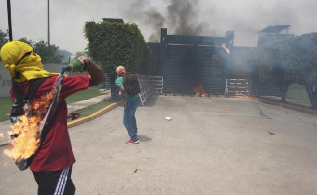 Los jóvenes aventaron bombas molotov, cohetones y piedras a la puerta principal del 27 Batallón de Infantería. Después atacaron el cajero automático de Banjercito. Foto: SALVADOR CISNEROS. EL UNIVERSAL