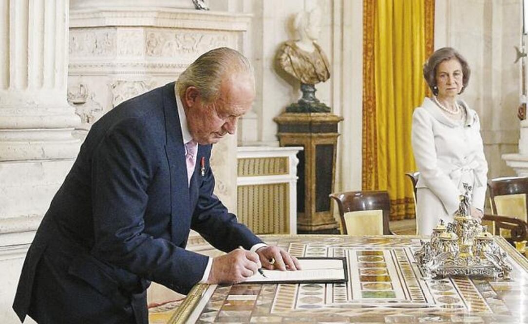 Imagen del 18 de junio de 2014 cuando el entonces rey Juan Carlos firma la ley orgánica sobre su abdicación en el Palacio Real de Madrid. (EFE. ARCHIVO)