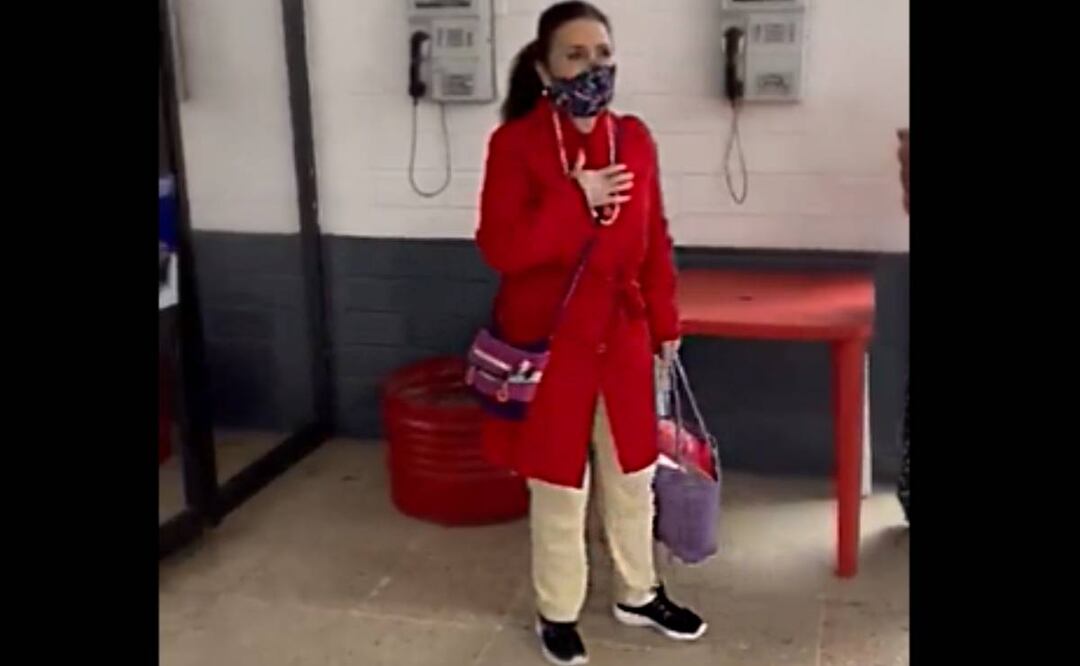 Portando abrigo rojo, tenis negros, patalón beige y con el cabllo recogido, agradeció con la mano en el pecho a sus acompañantes del penal. Foto: Captura de video