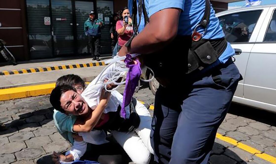 Un policía de Nicaragua arrastra el domingo en Managua a una opositora nicaragüense para detenerla, mientras otra intenta impedirlo, como parte de una oleada de arrestos ordenada por el presidente de ese país, Daniel Ortega (Foto: Reuters)