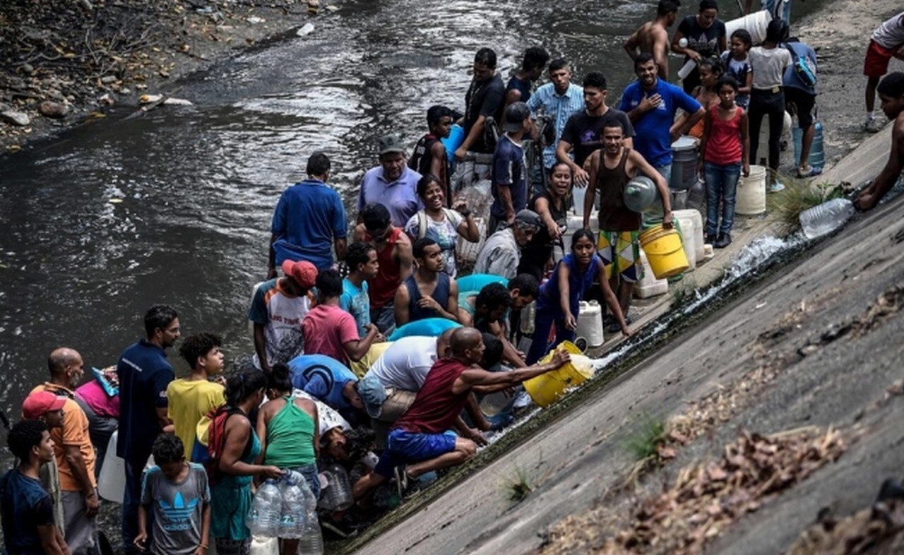  Por escasez, venezolanos recogen agua en río contaminado