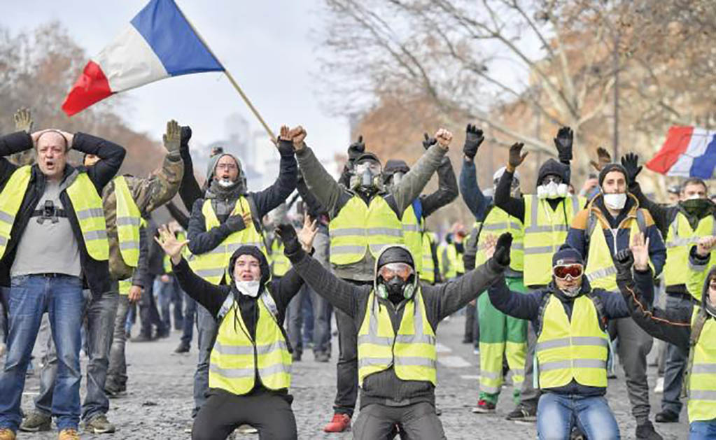 Manifestantes gritan consignas cerca del Arco del Triunfo, en París. La policía disparó gases lacrimógenos y cañones de agua contra los chalecos amarillos, ayer. (CHEN YICHEN. XINHUA)