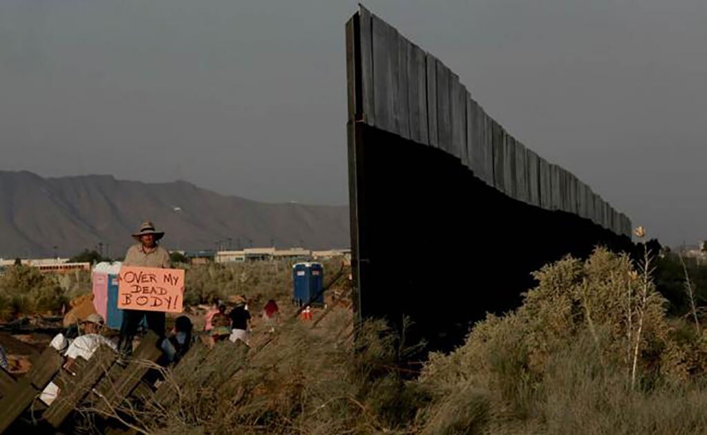 Un hombre sostiene un cartel durante una manifestación en contra de la construcción del muro entre México y Estados Unidos. Foto: Xinhua