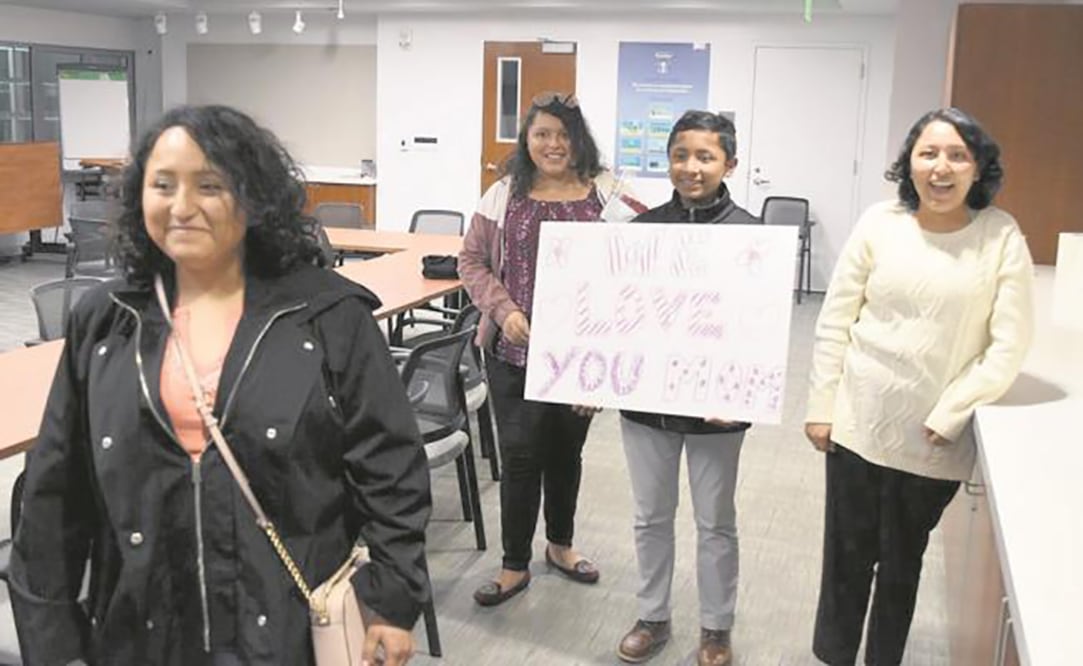 Las tres hijas y el hijo de María Mendoza esperan la llegada de su mamá en el aeropuerto de San Francisco, California, con un letrero que dice “Te amamos, mamá”. Foto: CORTESÍA
