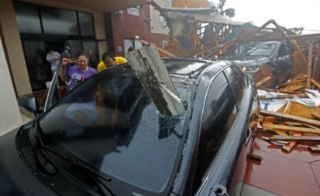 Una mujer y un hombre revisan su vehículo por el paso del huracán "Michael", el cual derrumbó el toldo en un hotel en Panama City Beach, Florida. Foto: AP