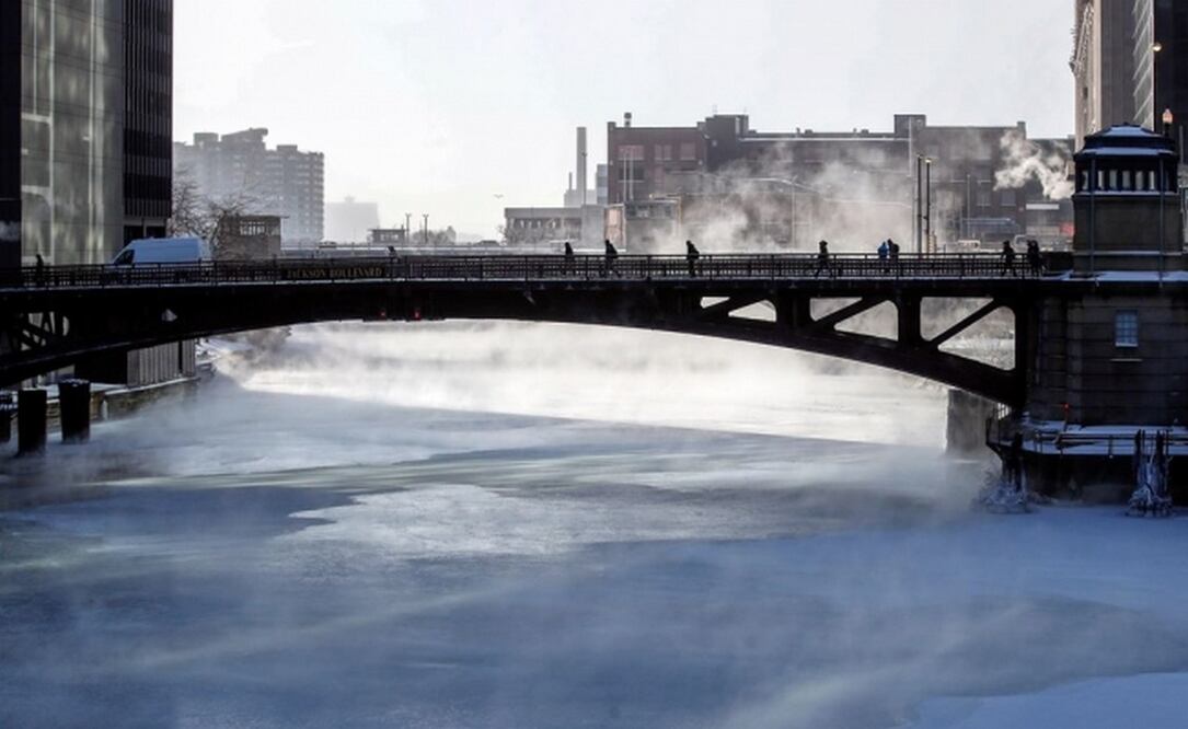 Varias personas cruzan un puente mientras la niebla se eleva desde el río Chicago (Foto: EFE)