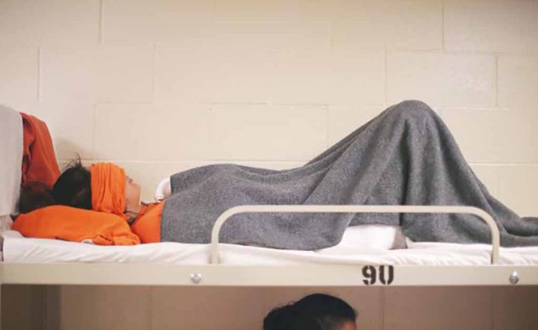 Una inmigrante descansa en el dormitorio de un centro de detención, en Adelanto, California (ARCHIVO. REUTERS)